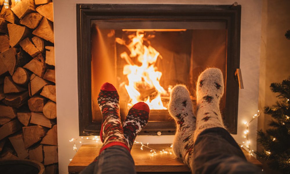 Lazy winter day in front of fire in fireplace. Human legs in Christmas socks in front of fireplace.